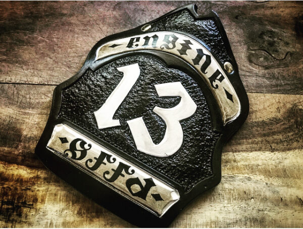 A hard-carved and hand-painted fire helmet shield by Smoked Leather.