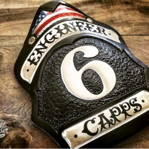 A hard-carved and hand-painted fire helmet shield by Smoked Leather.