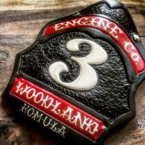 A hard-carved and hand-painted fire helmet shield by Smoked Leather.