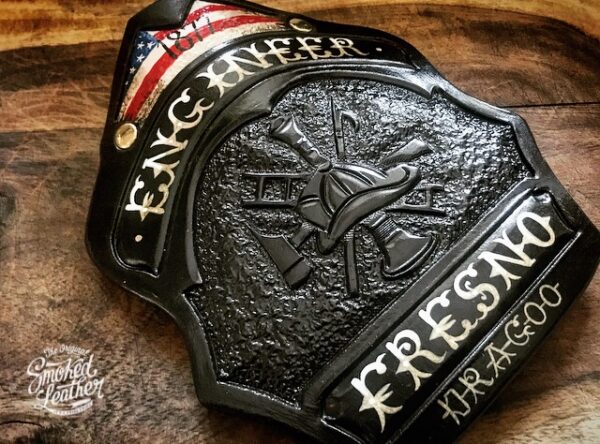 A hard-carved and hand-painted fire helmet shield by Smoked Leather.