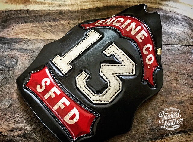 A hard-carved and hand-painted fire helmet shield by Smoked Leather.